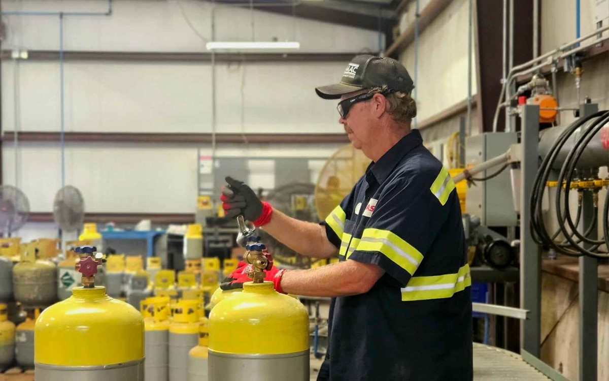 A man working with two yellow and silver cylinders 