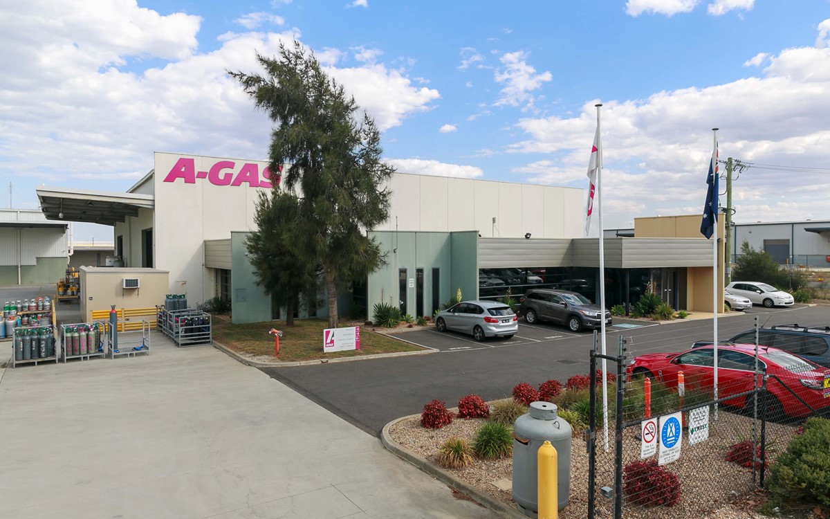A wide angle shot of the outside of the A-Gas in Australia building, there is one big building and some trees around it 