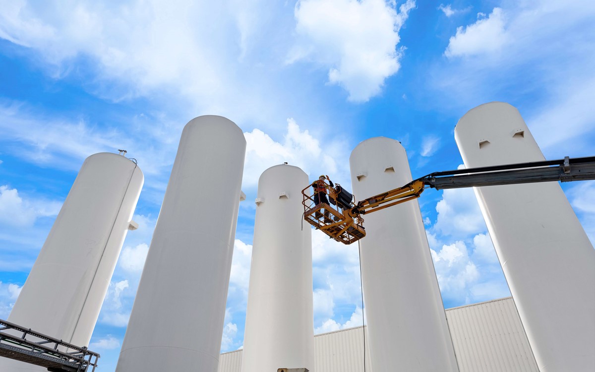Five white recovery separator towers with an operator on a platform 
