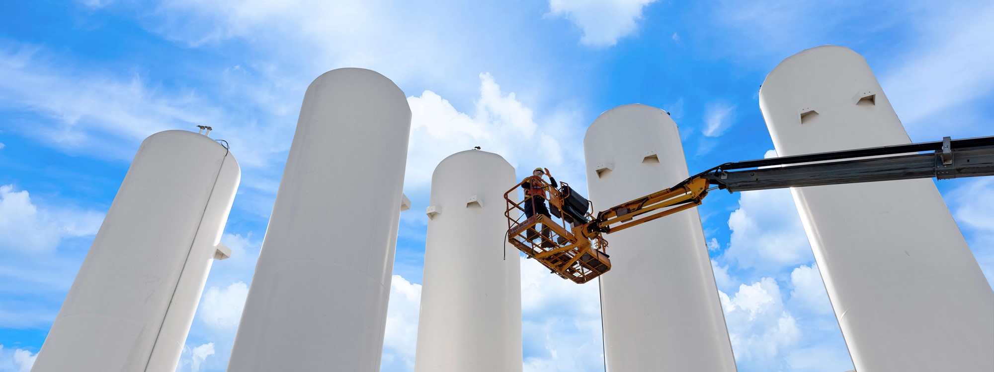 Five white recovery separator towers with an operator on a platform 