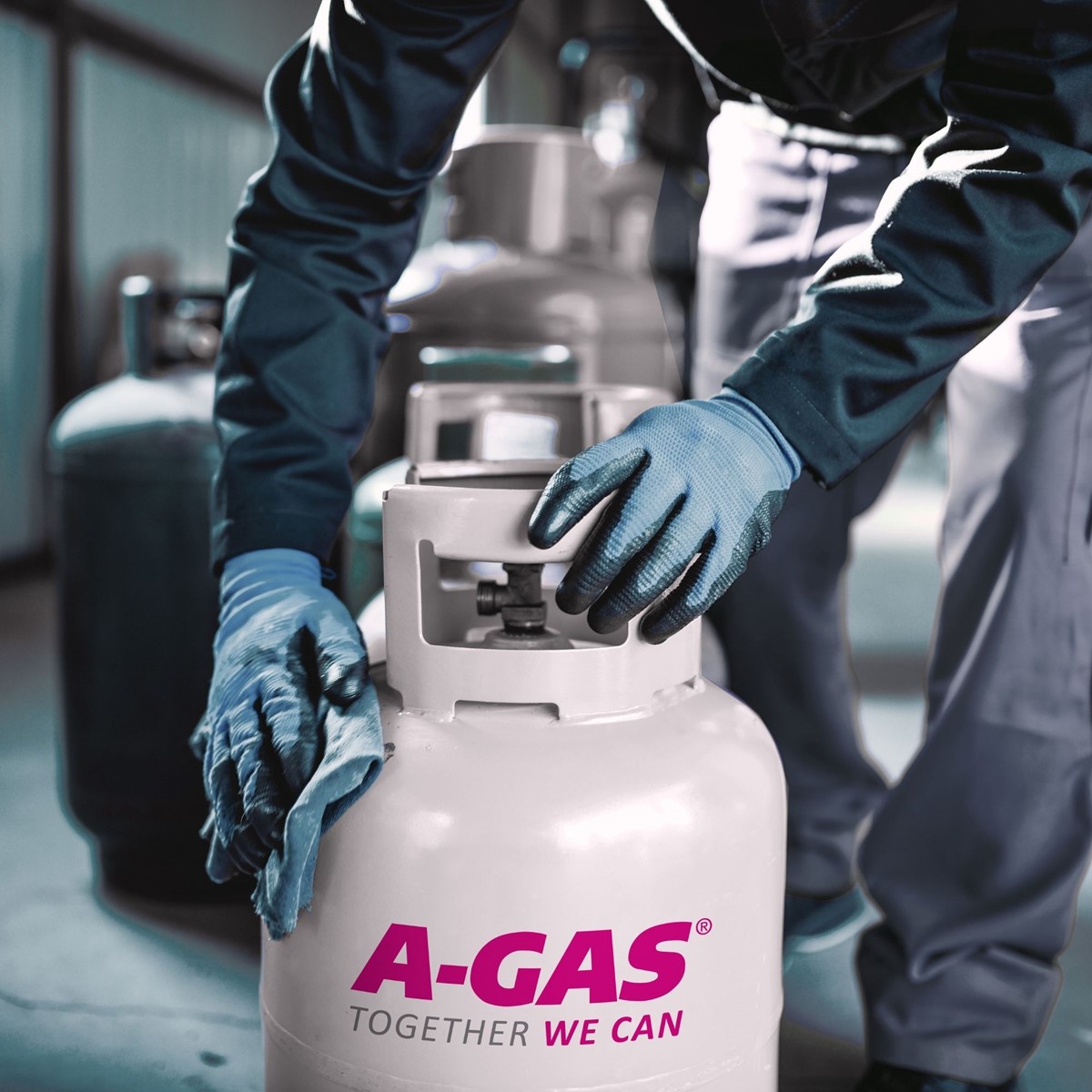 engineer with blue gloves handling and cleaning A-Gas branded gas cylinder