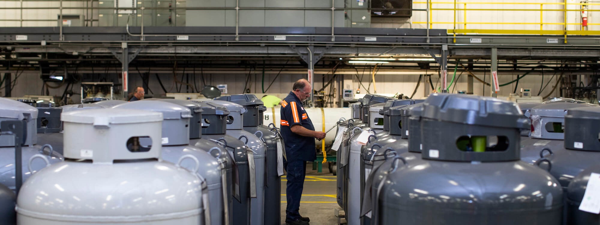 A person stood in between two rows of industrial gas cylinders