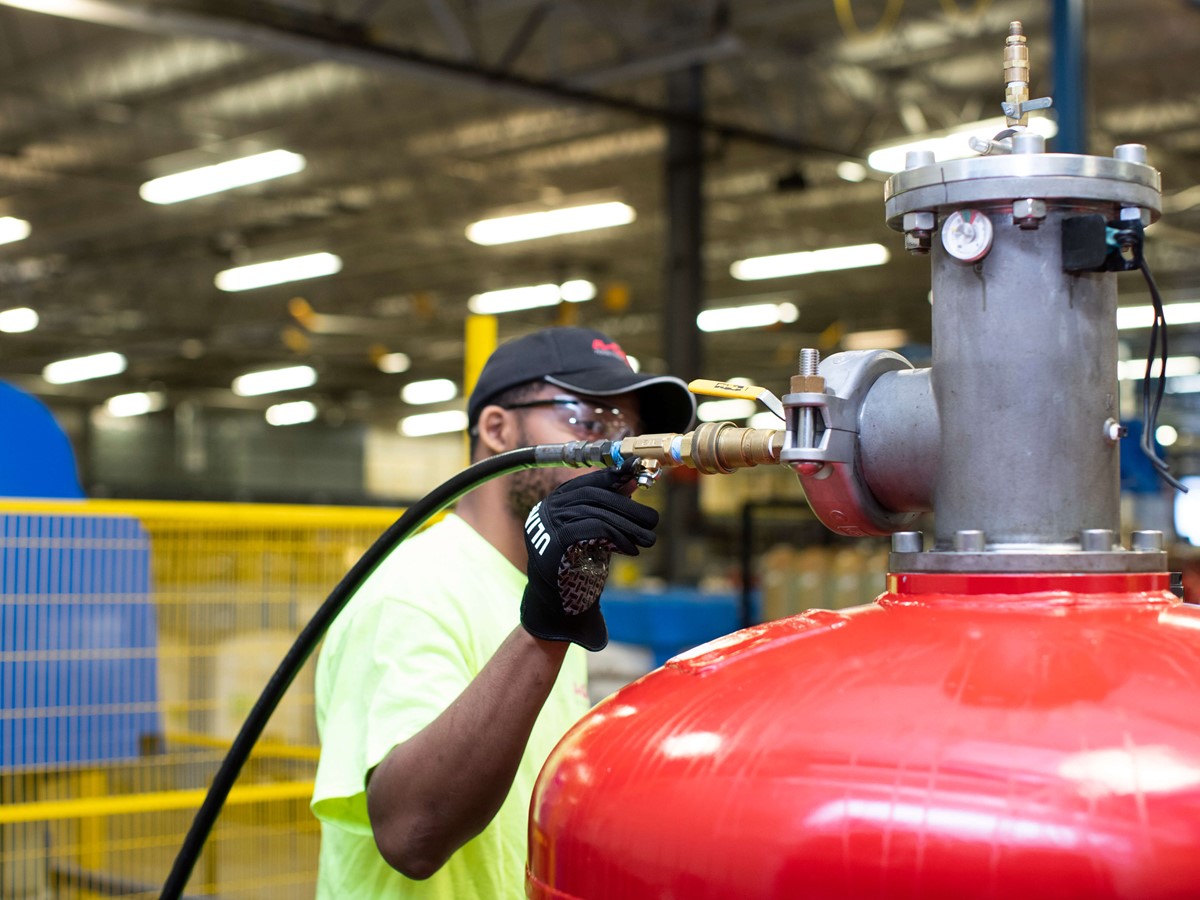 A close up of a person working with a large red half ton cylinder