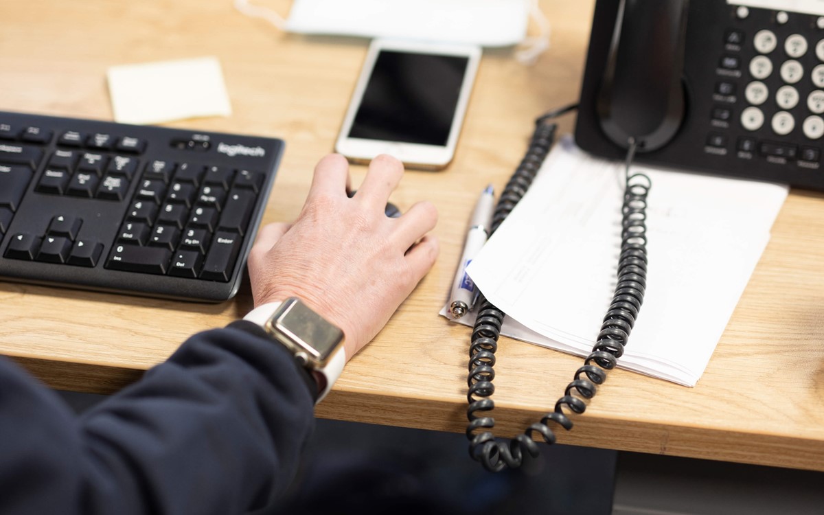 close up desk shot including mobile phone, telephone and hand operating mouse