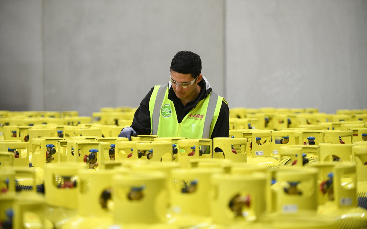 A man working in the middle of stacked cylinders in a warehouse 