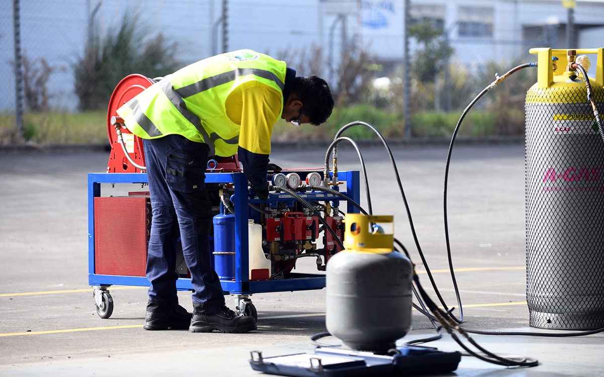 A man in a yellow high-vis jacket working with recovery equipment and two cylinders on-site