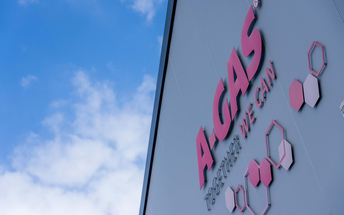 The pink A-Gas logo with hexagons on the side of a building 