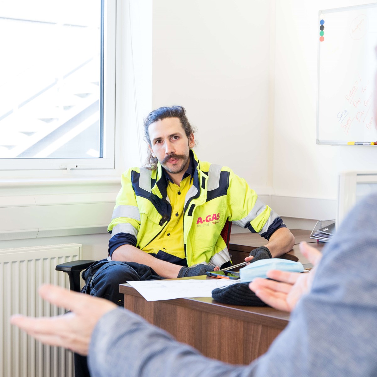 Two men sat opposite each other at a desk talking