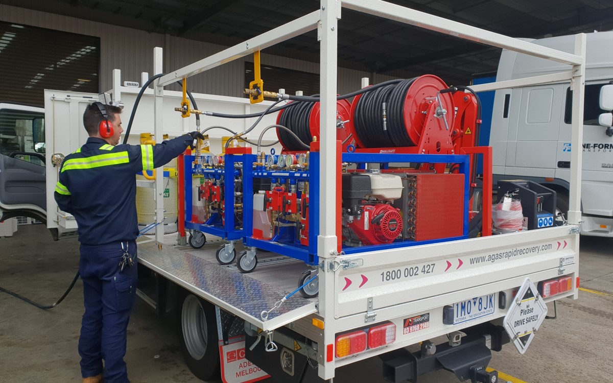 Man working with equipment at the back of a white truck