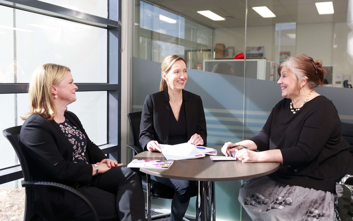 Three women sat around a table in a meeting