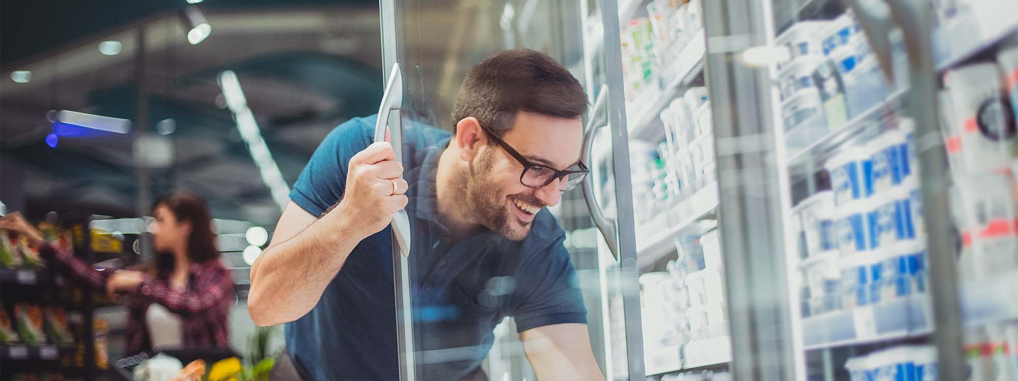 man in supermarket shopping for goods from chiller cabinet