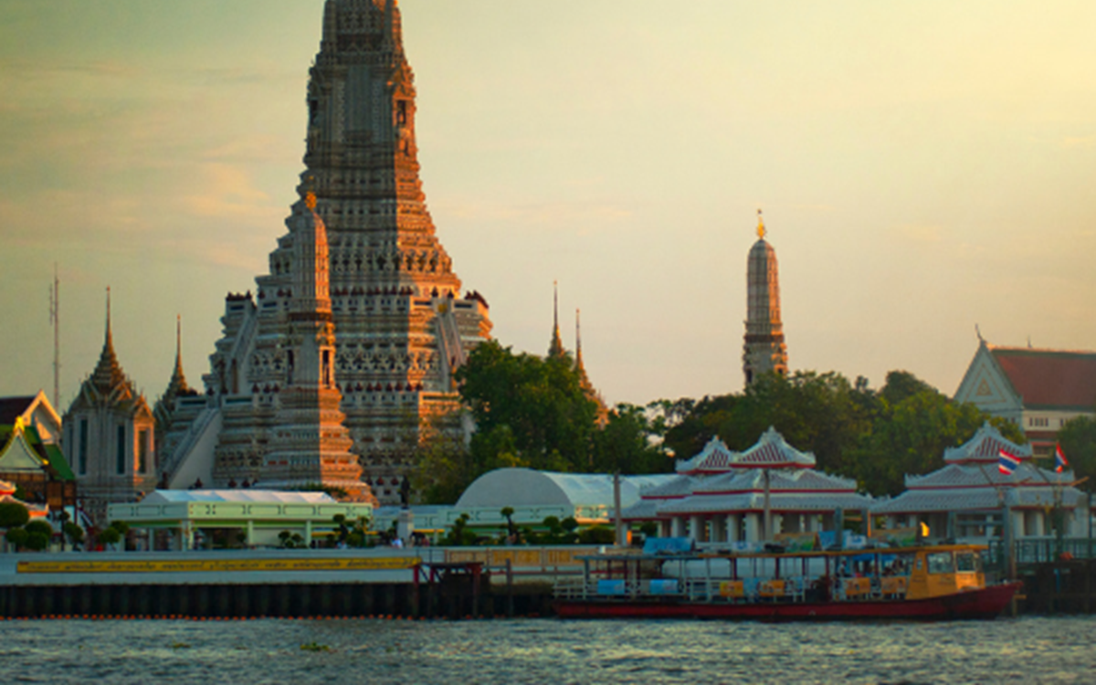 An image of traditional buildings in Thailand with a sunset behind them